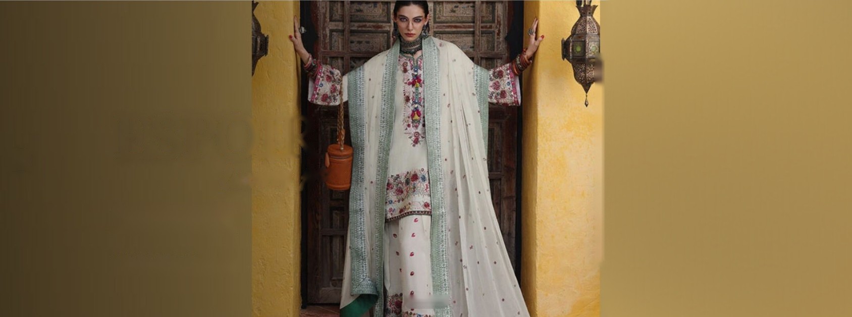 Model in an ivory embroidered luxury pret outfit standing in a carved wooden doorway