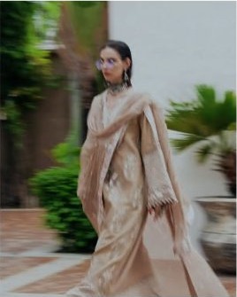 Model in a beige outfit walking outdoors
